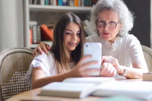 A picture of a grandmother and grandchild looking at a mobile phone and considering where to get technical support help.